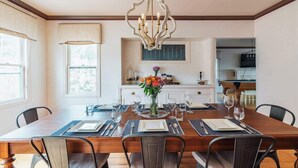 A dining room with a wooden table set for six, a chandelier, and a vase of flowers. - DT Flag | Epic Game Room | AC | Hot tub | Fire Pit (Flagstaff)