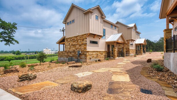 Una casa de dos pisos con base de piedra y un amplio camino de entrada.