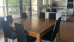 A spacious kitchen with white cabinets, a wooden dining table with black chairs, and a sliding glass door leading to a deck.