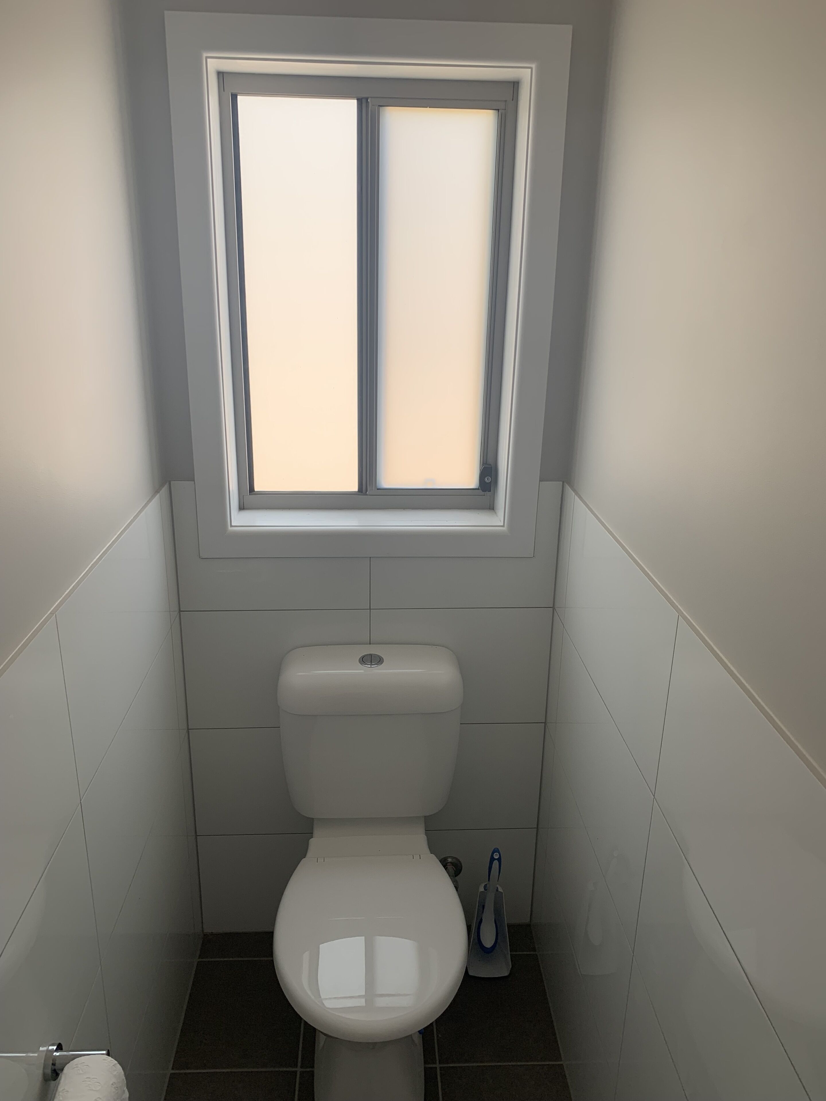 Une petite salle de bain compacte, équipée de toilettes, d’une fenêtre et d’une pompe à eau manuelle.