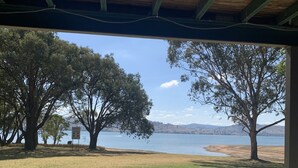 A covered outdoor area with a view of a lake and trees.