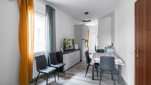 A modern kitchen with a dining area, a wooden door, and a view of the outside.
