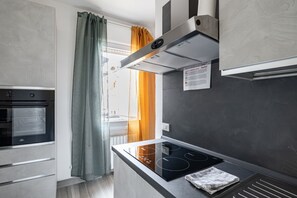 Et moderne køkken med indbygget ovn, komfur og emhætte.