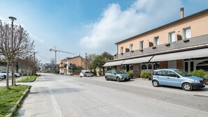 A street with parked cars, buildings, and a construction crane in the background.
