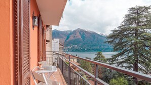 Varanda com mesa e cadeiras, com vista para um lago e montanhas.
