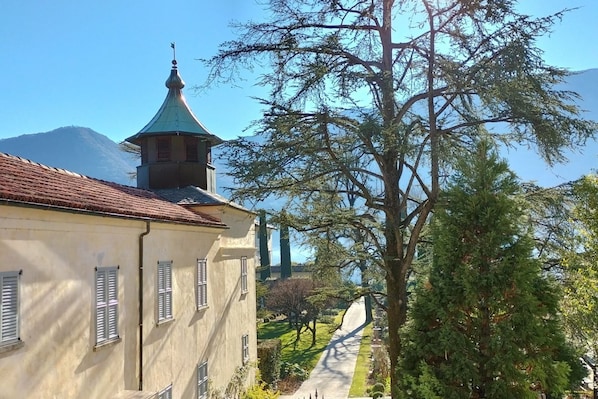 A building with a green roof, a tower with a conical roof, and a tree in the foreground.