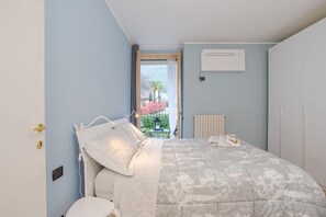 Ein Schlafzimmer mit Bett, Heizkörper, Klimaanlage und Blick ins Freie.