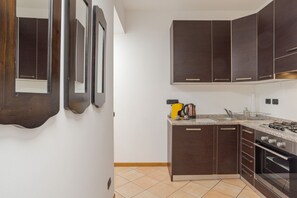 A modern kitchen with dark cabinets, a gas stove, and a coffee maker. - GuestHost - Cozy 60m2 apartment, perfect for two people, located on the 1st floor of a building with lift.The property is located on the road that connects Como and Menaggio, a few steps from the town center and just 300 meters from the Ossuccio lido, a  (Tremezzina)