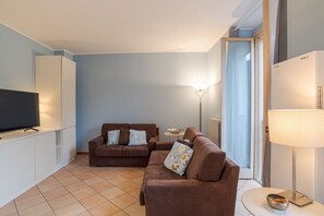Ein Wohnzimmer mit Fernseher, zwei Sofas, einer Lampe und einer Heizung.