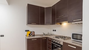 Une cuisine avec des meubles de rangement de couleur sombre, une cuisinière à gaz, un four et un four à micro-ondes.