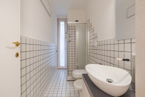Een badkamer met een wit wastafel, toilet en douche.
