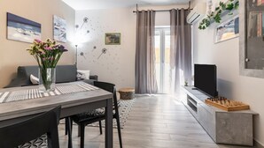Una sala de estar moderna con comedor, televisor de pantalla plana y un tablero de ajedrez.