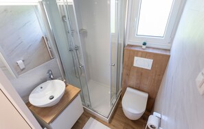 Un bagno compatto con doccia vetrata, lavabo e servizi igienici.