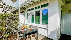 Un patio con una mesa dispuesta para el desayuno, con vistas a un jardín verde.
