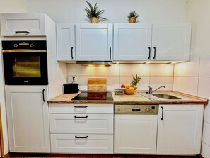 A kitchen with white cabinets, a built-in oven, a dishwasher, and a sink. - Villa Meernixe - nur 100 m bis zum Strand, Zentrumsnahe Ferienwohnung - Villa Meernixe Fewo 10 (Binz)