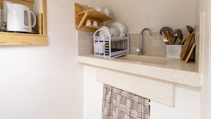 A kitchen with a sink, wooden shelves, and a dish rack. - GuestHost - White Lotus Apartment (Ostuni)