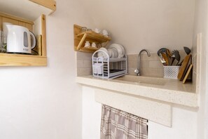 Una cocina con un lavamanos, repisas de madera y un escurreplatos.