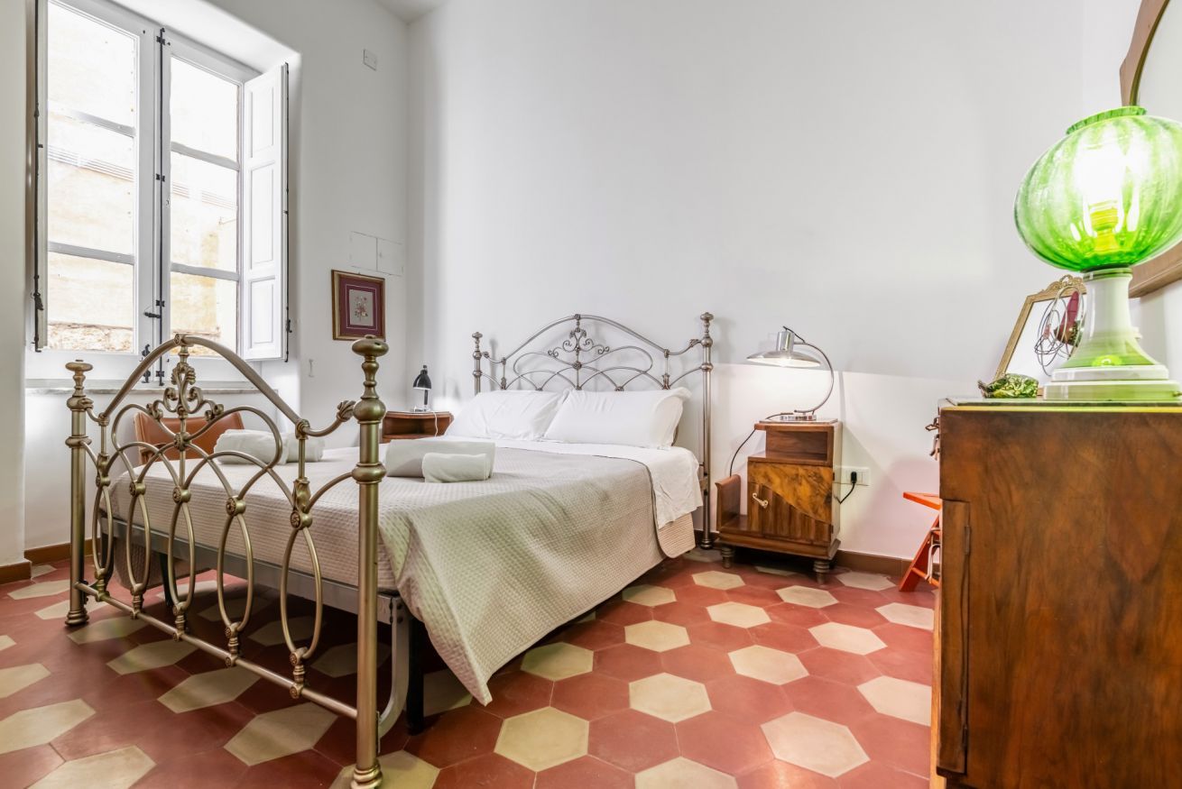 Una habitación con una cama, una mesita de noche, una lámpara y un armario de madera.