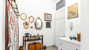 Une pièce avec une commode blanche, un miroir, un meuble en bois et un mur orné d’un motif.