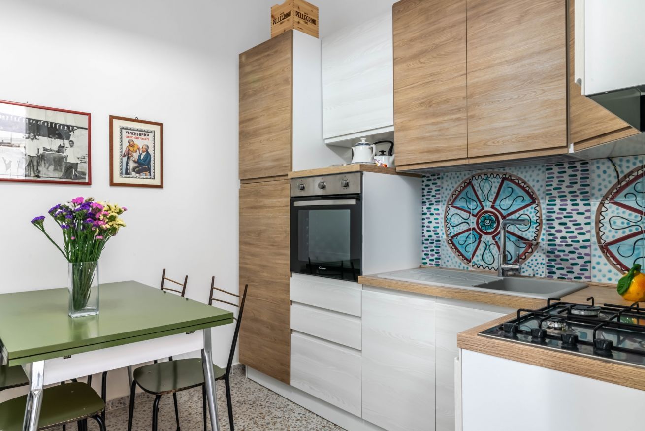 Et moderne køkken med træskabe, indbygget ovn, gasblus og dekorativt backsplash.