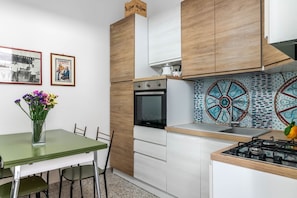 Une cuisine moderne avec des meubles en bois, un four encastré, une cuisinière à gaz et un crédence décorative.