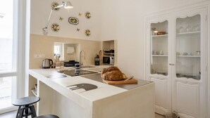 A modern kitchen with a central island, a sink, a microwave, and a cabinet with glass doors. - GuestHost - Before Sunset Appealing Apartment with Terrace (Ostuni)