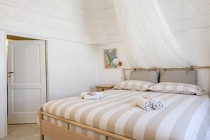 A bedroom with a bed, a bedside table, a nightstand, a door, and a wall-mounted light fixture. - GuestHost - Before Sunset Appealing Apartment with Terrace (Ostuni)