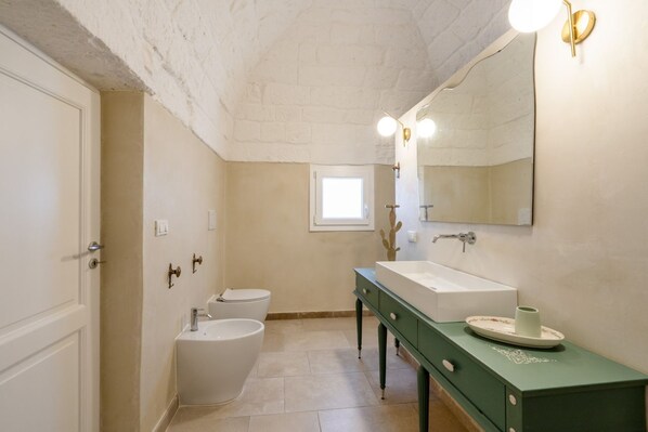 A bathroom with a white bathtub, a white toilet, a green vanity with a sink, and a large mirror.