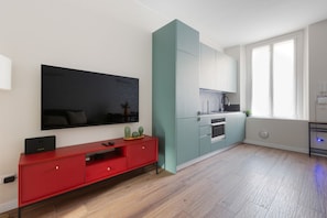 A modern kitchen with a TV, red entertainment unit, and teal cabinetry. - GuestHost - Modern apartment of approximately 45sqm, perfect for 2 people, located on the fourth floor of a building with lift.The apartment is located 3.6km from Linate Airport and a short distance from the Monzino Cardiology Center and the Milano-Fo (Milano)