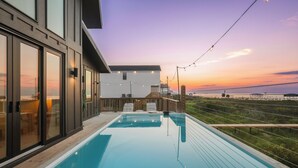 A modern pool area with a clear view of the sunset and ocean.