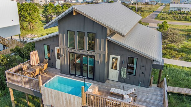 A large house with a swimming pool, deck, and multiple windows.