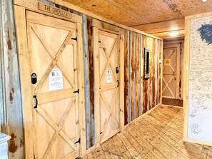 A hallway with wooden doors labeled 'The Cove' and 'The Overlook,' leading to a room with a view. - 2 Bed Boutique Suite at The Goat Pen - Gizzard South Room (Tracy City)