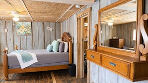 Un dormitorio rústico con una cama de madera, un aparador y un espejo grande.