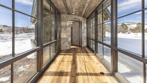 A corridor with large windows, wooden flooring, and stone walls. - Telluride Ranch / Mountain Views, Hot Tub & Fire Pit (Placerville)