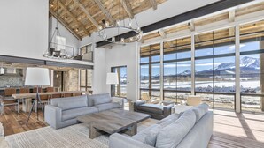 A spacious living area with a large sofa, a coffee table, and a view of mountains through large windows. - Telluride Ranch / Mountain Views, Hot Tub & Fire Pit (Placerville)