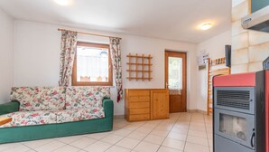 Una sala de estar con un sofá floral, un aparador de madera, un electrodoméstico rojo y una ventana con cortinas.