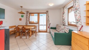 Una habitación acogedora con una mesa de comedor, sillas, un sofá y una ventana con cortinas.