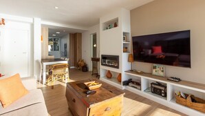 Un salon moderne doté d’un grand téléviseur à écran plat, de meubles en bois et d’étagères intégrées où sont exposés des objets décoratifs.
