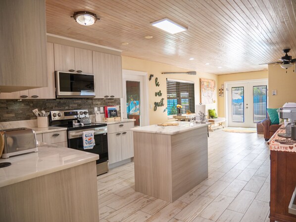 A modern kitchen with wooden cabinets, a microwave, an oven, and a large island.
