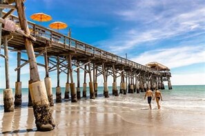 A wooden pier extending into the sea with two umbrellas on it. - Private Saltwater pool, 386 steps to ocean, and amazing rocket launch view (Cocoa Beach)