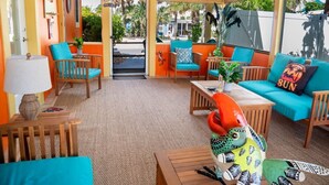 Une pièce aux couleurs vives, avec des murs orange, des meubles turquoise et orange, une table en bois et une sculpture d’oiseau décorative.