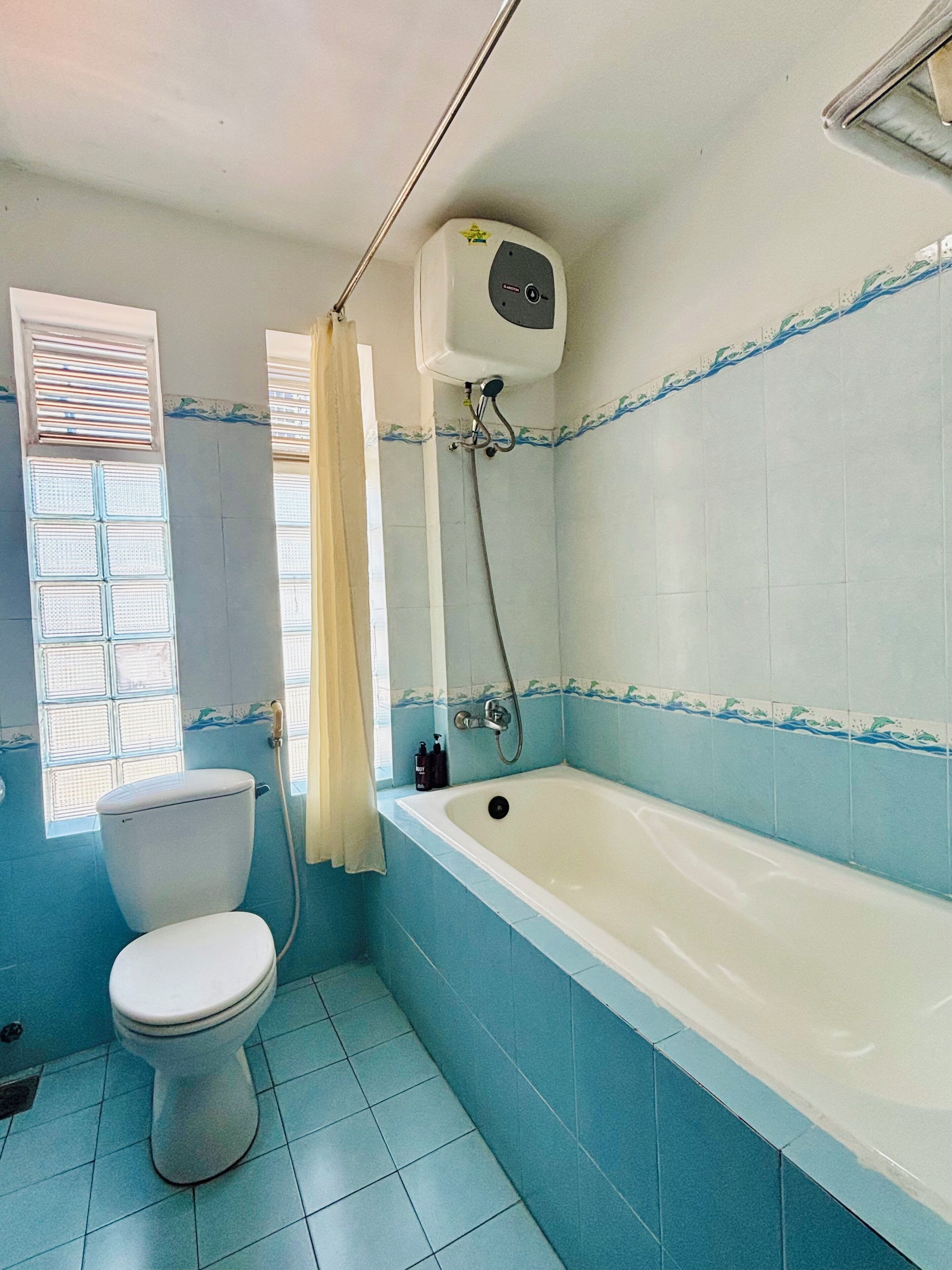 Een badkamer met toilet, bad en raam met zonwering.