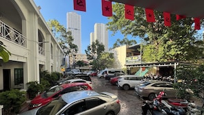 A street view with parked cars and motorcycles, buildings with balconies, and a clear sky. - Hai Au Hotel (Nha Trang)