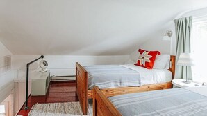 Een slaapkamer met twee eenpersoonsbedden, een nachtkastje, een lamp en een radiator.