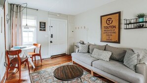 Een woonkamer met een bank, een salontafel en een eethoek met stoelen.