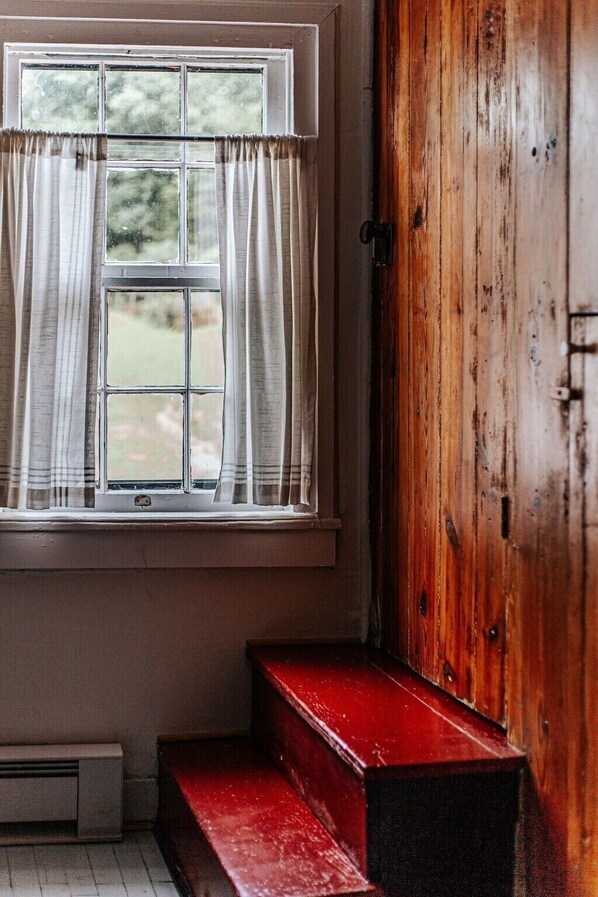A room with a window, a wooden door, and a red bench.