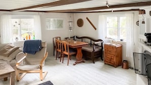 A cozy room with a wooden dining table, chairs, a sofa, and a small cabinet.