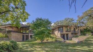 A two-story house with a stone facade, a covered porch, and a small tree in the front yard. - Midcentury beauty with modern updates, gorgeous views (Grafton)
