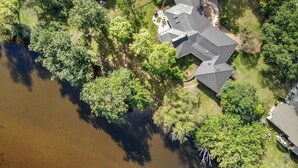 An aerial view of a house surrounded by dense greenery and a body of water. - Midcentury beauty with modern updates, gorgeous views (Grafton)