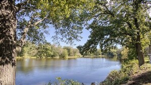 A calm lake surrounded by trees and greenery. - Midcentury beauty with modern updates, gorgeous views (Grafton)